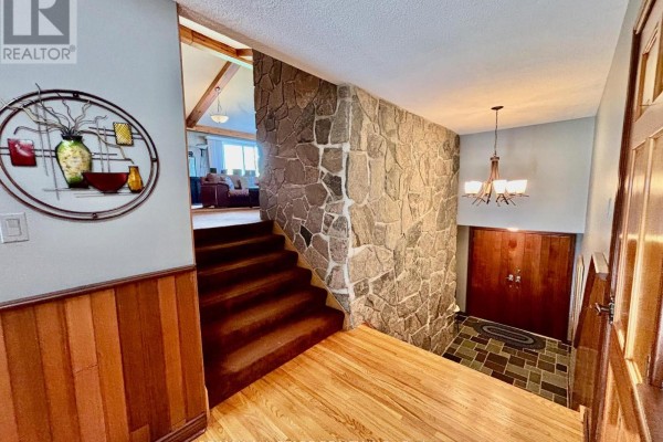 Foyer with wood paneling, a large stone feature wall, and a wooden staircase. - 1374 Regional Road 12 Road W, Brock