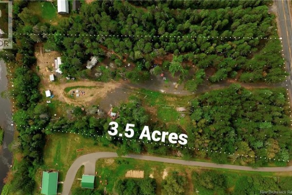 Aerial view of 3.5 acres of land with trees, cleared areas, and buildings along Salmon River. - 1374 Route 116, Salmon River Rd