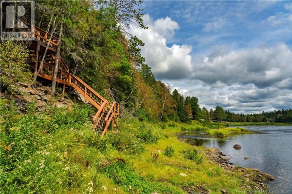Wooden staircase descending a grassy, wooded bank towards the Salmon River under a cloudy sky. - 1374 Route 116, Salmon River Rd