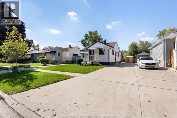View of the house from the street showing the driveway and adjacent properties. - 1375 Bernard Road, Windsor