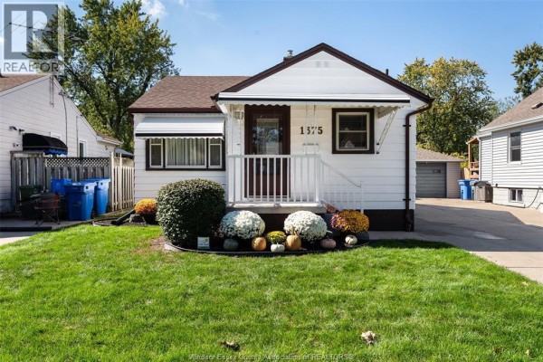 Front view of the white house with a manicured lawn and seasonal decorations. - 1375 Bernard Road, Windsor