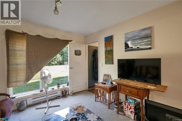 Living area with television, window, and door leading outside. - 1376 Hooley Rd, Quadra Island