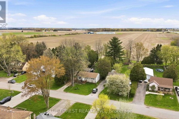 Aerial view of a suburban street with single-family homes and surrounding agricultural fields. - 1376 Kostis Avenue, London East