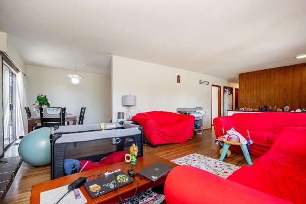Living and dining areas with red furniture, playpen, and dining table. - 13760 Bentley Road, Surrey