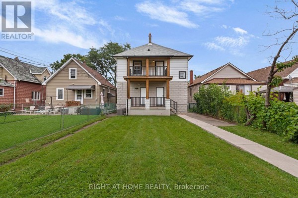 Rear exterior of the multi-family home, with a grassy backyard and neighboring houses. - 1379-1381 Pierre Avenue, Windsor