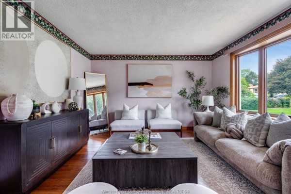 Living room with a large sectional sofa, coffee table, and decorative sideboard. - 1379 Oxford Ave, Kingsville