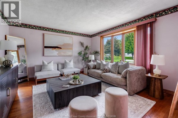 Living room with sectional sofa, large window with view of backyard and trees. - 1379 Oxford Ave, Kingsville