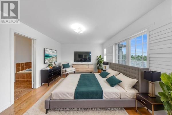 Bedroom with a king-size bed, dresser, armchair, and ensuite bathroom entrance. - 138 Angus Drive, Ajax
