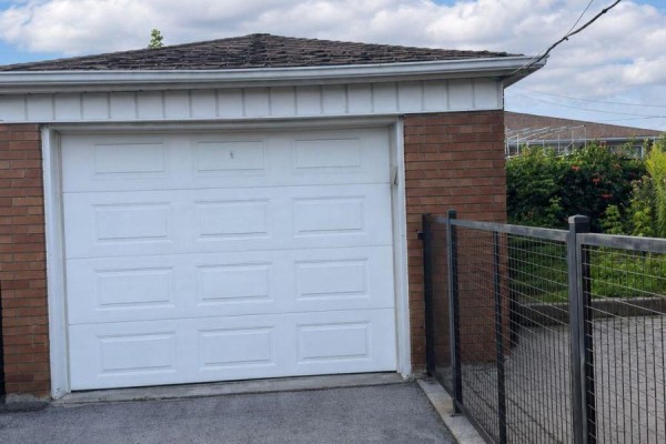 White paneled garage door on brick house with metal fence. - 138 Lomar Drive, Toronto