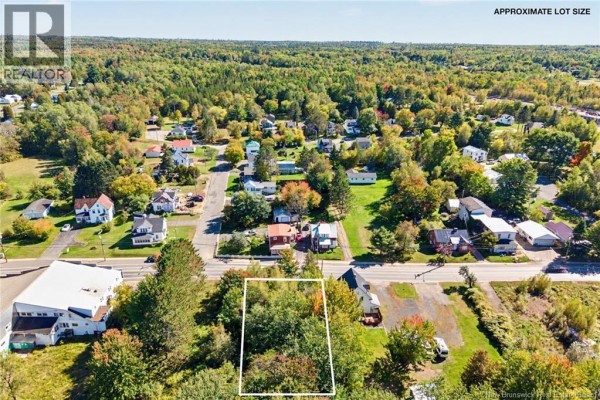 Aerial view of the property lot outlined in white, surrounded by houses and trees in a neighborhood. - 138 Main Street, Chipman