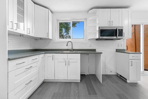 White kitchen with grey countertops, white subway tile backsplash, and stainless steel appliances. - 138 Rue Bourgeau N., Gatineau