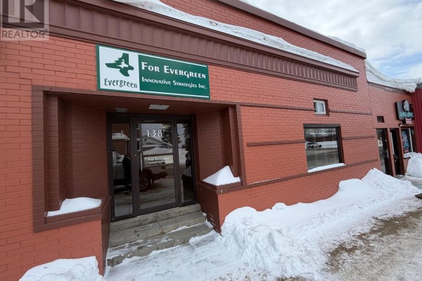 Boardroom with a large dark wood table, red office chairs, and beige walls. - 138 Third Street, Cochrane