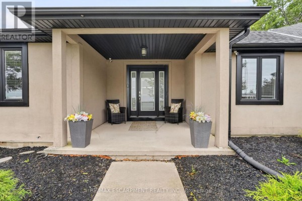 Covered front porch entrance with double glass doors, two chairs, and decorative planters. - 1380 Eighth Avenue Louth, St  Catharines
