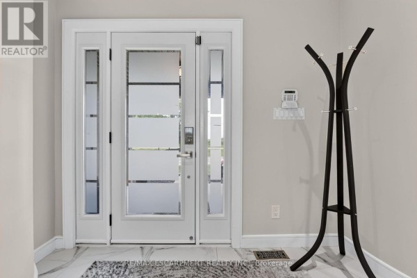 Interior view of a bright foyer with white double doors featuring frosted glass panels and a coat rack. - 1380 Eighth Avenue Louth, St  Catharines