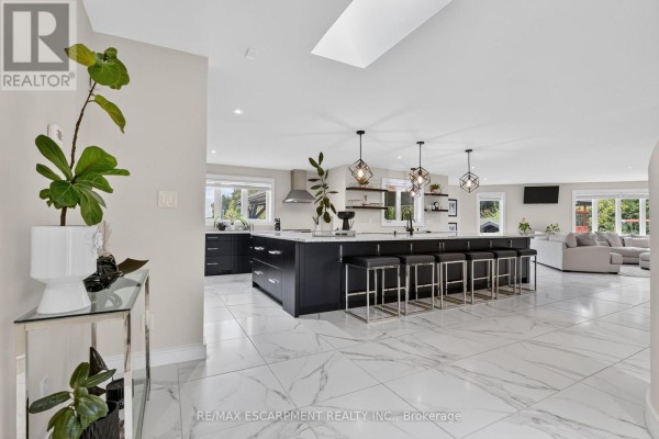 Spacious open-concept kitchen and living area with a large island, dark cabinets, and white marble floors. - 1380 Eighth Avenue Louth, St  Catharines