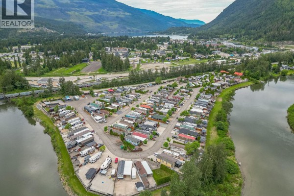 Aerial view of a waterfront RV resort with numerous RVs, cabins, and mountain views. - 1383 Silver Sands Road Unit# 109, Sicamous