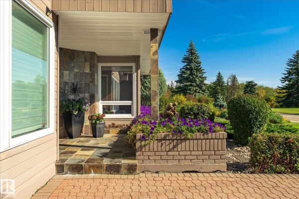 View of the covered entryway with a tiled floor and decorative plants. - 13862 Ravine Dr Nw, Edmonton
