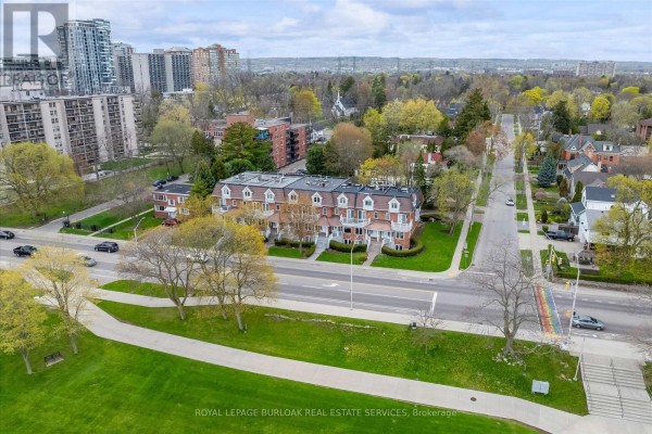 Aerial view of townhouses on Lakeshore Road with a park, lake, and city skyline in the background. - 1389 Lakeshore Road, Burlington