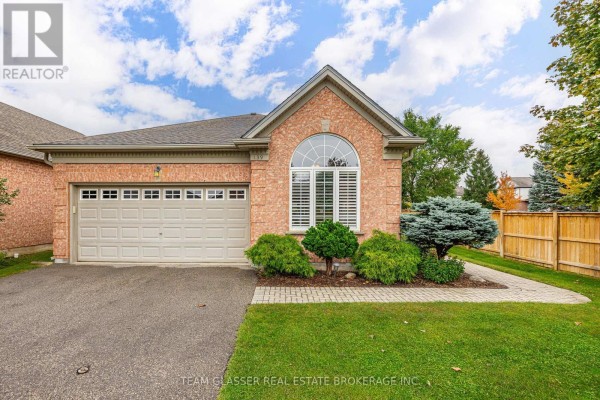Front exterior of brick townhouse with garage, arched window, and landscaped garden. - 139 - 2025 Meadowgate Boulevard, London South