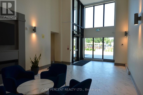 Apartment building lobby with large windows and doors looking out to the exterior, with modern lighting. - 139 - 50 Herrick Avenue, St  Catharines