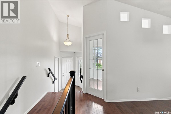 Interior view of a hallway with hardwood floors, white walls, and a staircase. - 139 Brainerd Crescent, Saskatoon