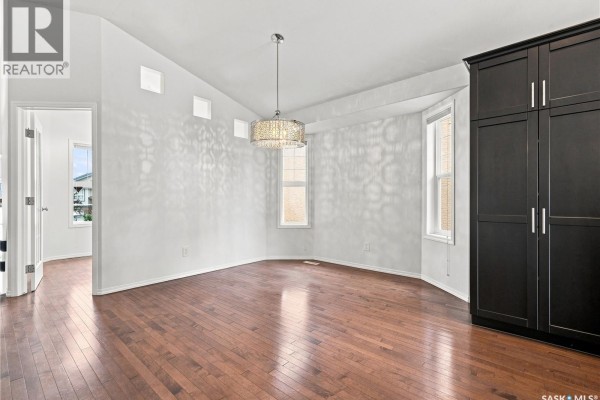 Interior view of a room with hardwood floors, white walls, a bay window, and a dark wardrobe. - 139 Brainerd Crescent, Saskatoon