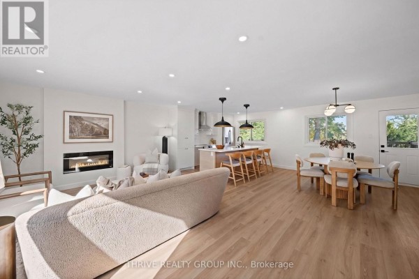 Open concept living, dining, and kitchen area with a fireplace and light wood floors. - 139 Deer Park Circle, London North