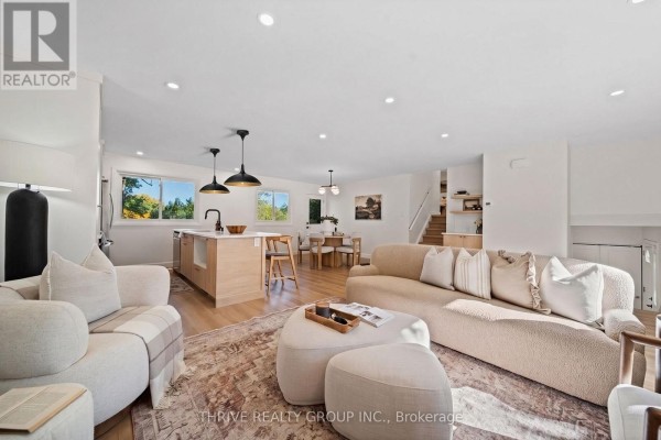 Living room with a sectional sofa, chairs, ottoman, and kitchen island in background. - 139 Deer Park Circle, London North