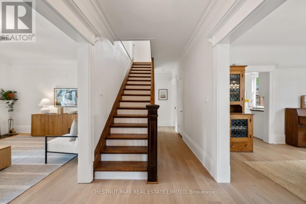 Attic bedroom with a skylight, white closets, a grey armchair, and a view into a bathroom. - 139 Hammersmith Avenue, Toronto