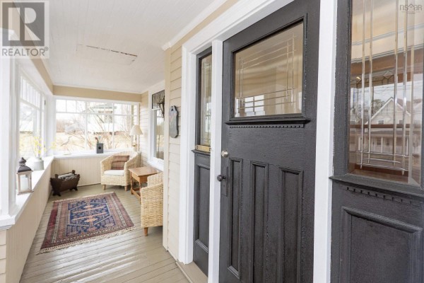 Sunroom with windows overlooking the street, featuring wicker furniture and a patterned rug. - 139 Main Street, Springhill