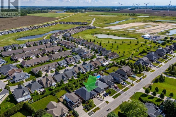 Aerial view of a suburban neighborhood with houses, ponds, and wind turbines in the background. - 139 New Lakeshore Road, Norfolk