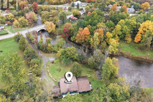 Aerial drone view of a house near a river and a bridge, with surrounding trees displaying vibrant autumn colors. - 139 Port Elmsley Road, Drummond/north Elmsley