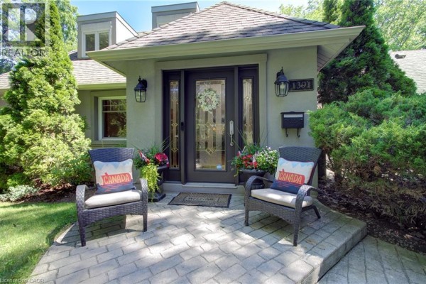 Close-up of the house entrance with double doors, flanked by decorative urns and wicker chairs on a stone patio. - 1391 Queen Victoria Avenue, Mississauga