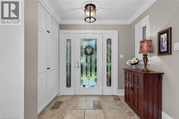 Foyer entrance with a glass-paned door, stone tile flooring, and built-in white storage cabinets. - 1391 Queen Victoria Avenue, Mississauga