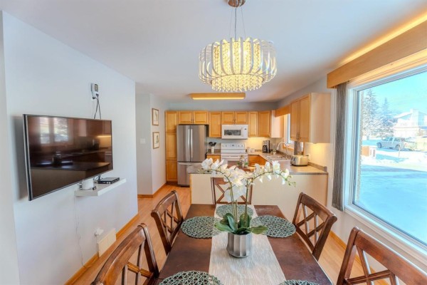 Dining area with a table, chandelier, and view of the kitchen and outside - 1392 Ravelston Avenue, Winnipeg