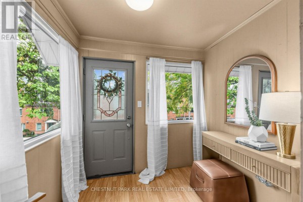 Sunroom entryway with a grey door, console table, bench, and large mirror. - 1394 Davenport Road, Toronto