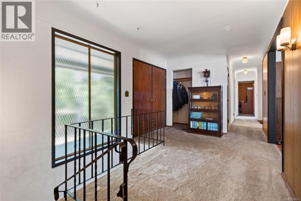 Interior hallway with beige carpet, wood-paneled walls, and doorways leading to rooms. - 1394 Seaview Rd, Black Creek