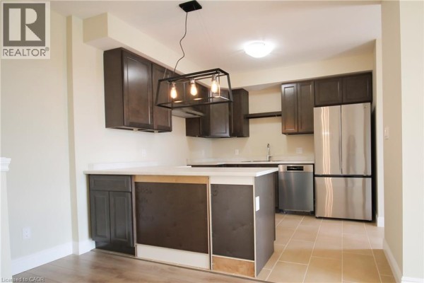 Empty dining area with light beige walls, wood-look flooring, and sliding glass doors. - 1395 Bleams Road Unit# 8, Kitchener