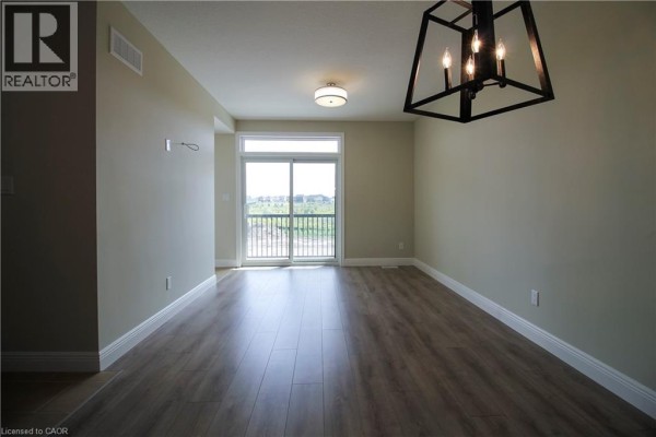 Corner kitchen with dark brown cabinets, a light countertop island, and tiled flooring. - 1395 Bleams Road Unit# 8, Kitchener