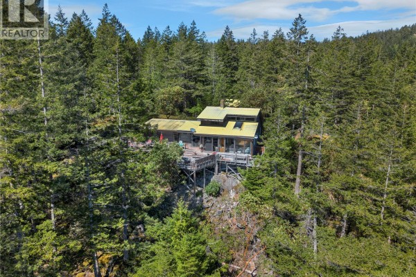 Aerial view of a house perched on a rocky outcrop surrounded by trees. - 1395 Manzanita Rd, Cortes Island