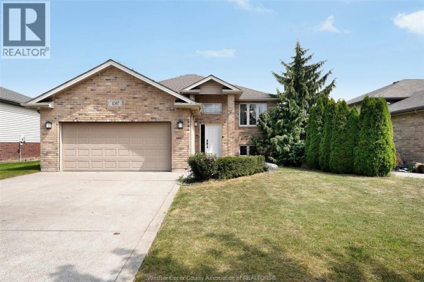 Exterior front view of a two-story brick house with a beige garage door and lawn. - 1397 Crosswinds Drive, Lakeshore