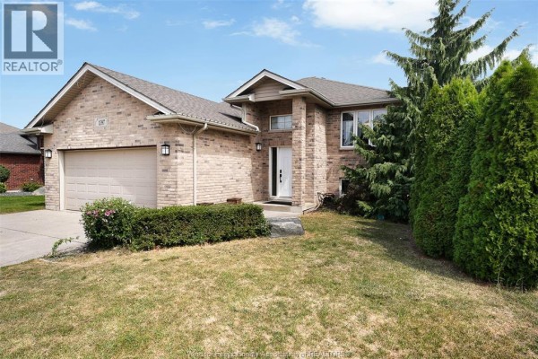 Front view of a brick house with a beige garage door, green lawn, and mature trees. - 1397 Crosswinds Drive, Lakeshore