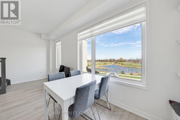 Dining area with a white table and grey chairs, adjacent to a large window. - 1399 Shevchenko Boulevard, Oakville