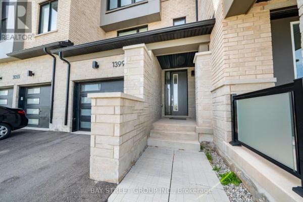 Entrance to the townhouse with a stone walkway, steps, and a glass-paneled front door. - 1399 Shevchenko Boulevard, Oakville