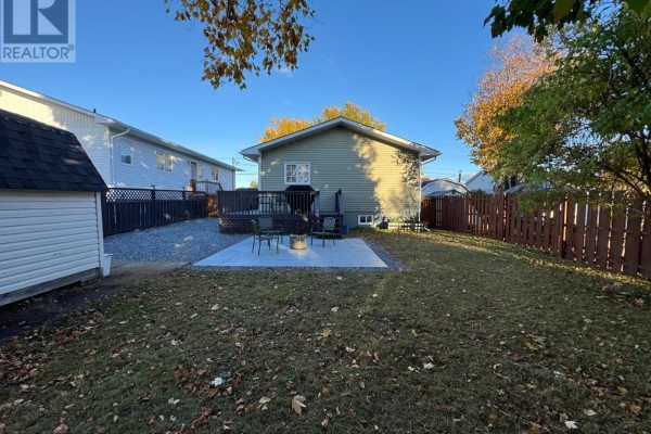 View of the backyard from the rear, showing a deck, patio, and shed. - 13a O'brien's Drive, Stephenville