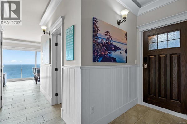 Entrance hall with tiled floor, white wainscoting, artwork, and view of the ocean. - 13b 1000 Sookepoint Pl, Sooke