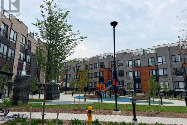 Tree-lined courtyard with playground equipment, benches, and a fire hydrant, set against townhouses. - 14 - 10 Liben Way, Toronto