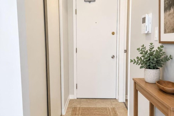Hallway with a white front door, closet, and a wooden console table with decor. - 14 - 140 Laurier Street, Casselman