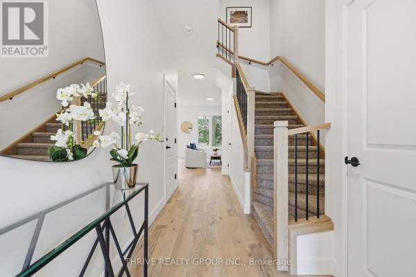 View down the hallway towards living area with stairs and a large oval mirror. - 14 - 279 Hill Street, Central Elgin