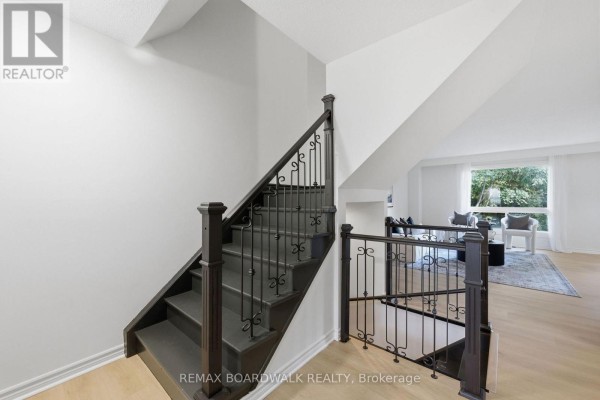 Dark wood staircase with ornate metal railings ascending to the upper floor. - 14 - 314 Stone Quarry Private, Ottawa